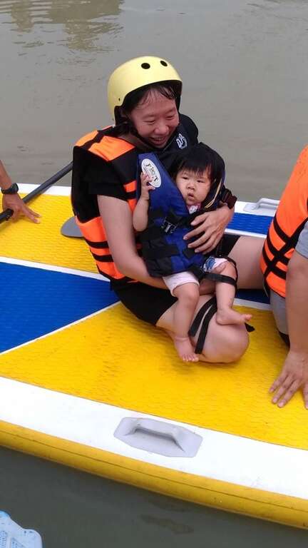 八个月大的小朋友穿着儿童专属救生衣，乘坐龙舟板体验爱河